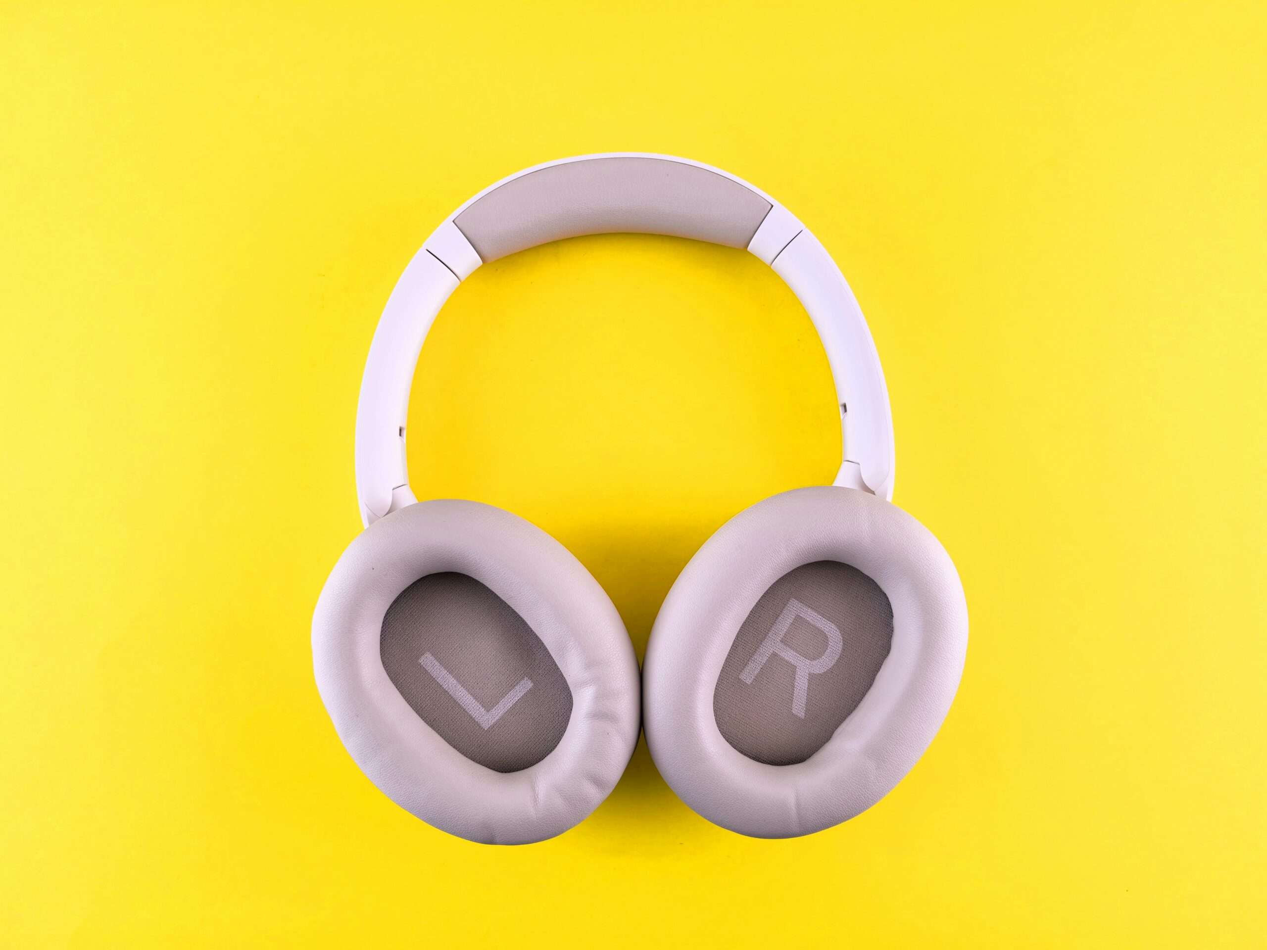 Stylish wireless headphones placed on a bold yellow surface, showcasing modern design and comfort.